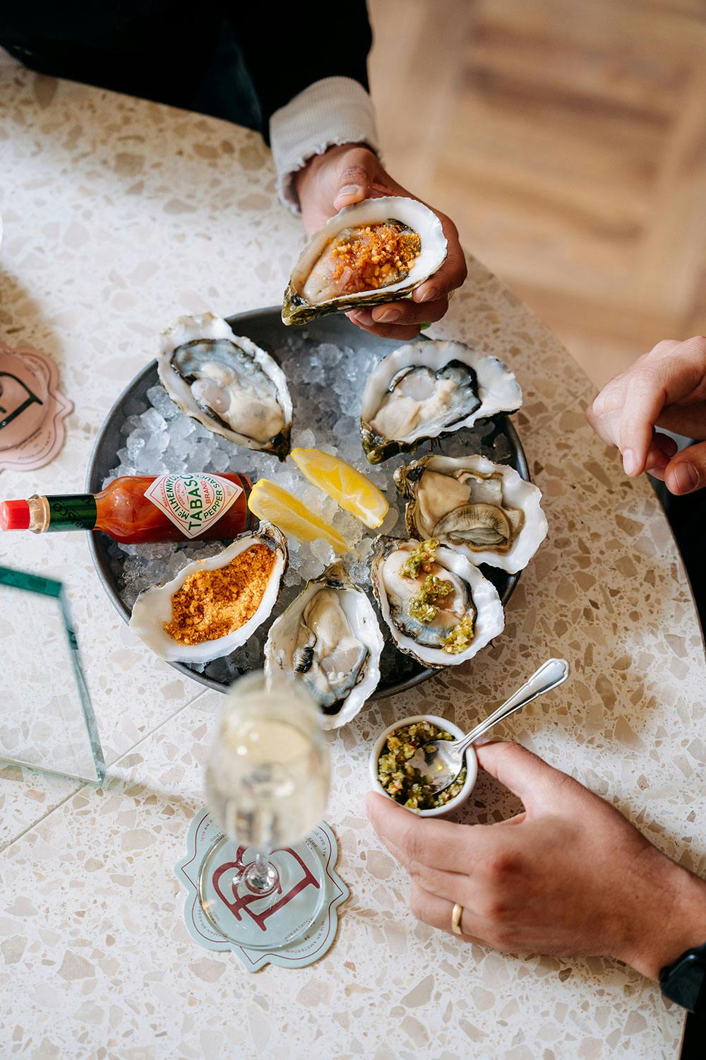 Tray of oysters on ice with hot sauce and lemon